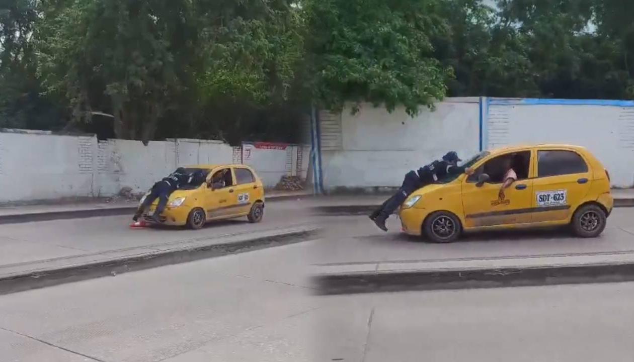 Momento en que agente está encima del capó del taxi.