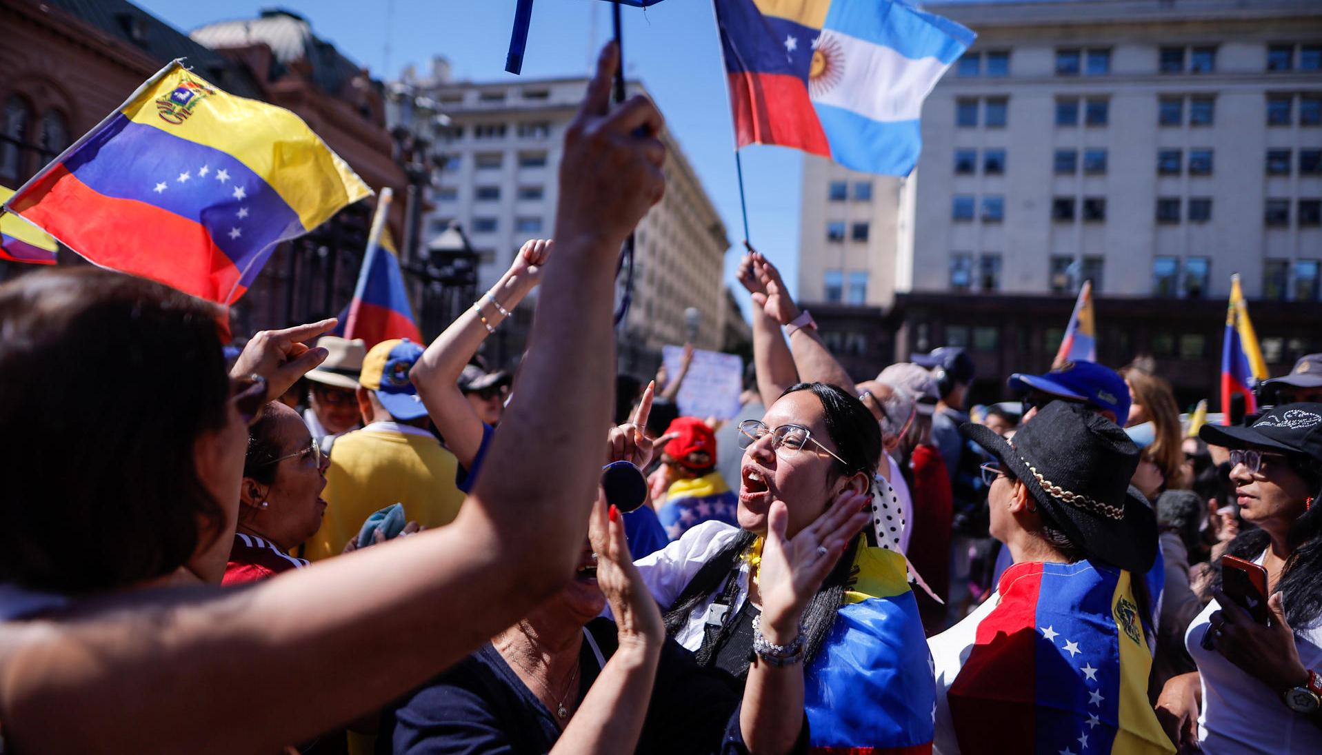 Personas agitan la bandera de Venezuela y gritan consignas este sábado en al Plaza de Mayo.