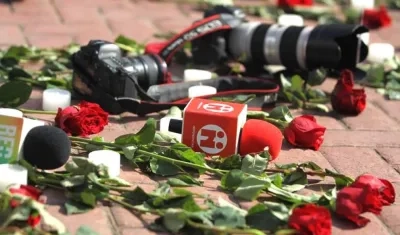 Cámaras y micrófonos de diferentes medios junto a rosas, en señal de rechazo al triple asesinato.