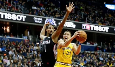 revor Ariza de los Washington Wizards (izq) defiende ante Stephen Curry.