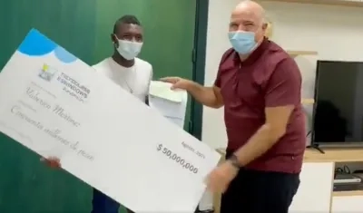 Yuberjen Martínez recibe el cheque de mano de Christian Daes. 