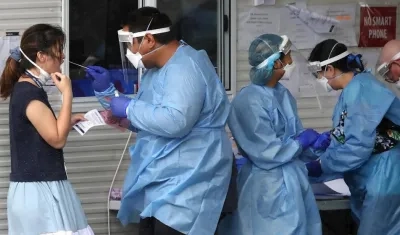 Un funcionario de la salud toma una muestra a una mujer en Australia, para detectar el Covid-19.