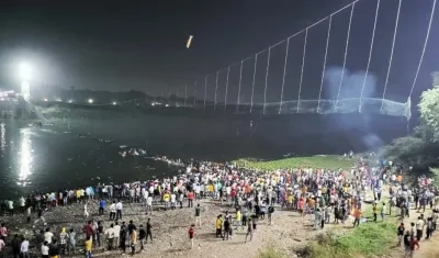 Decenas de personas aguardan luego de que un puente colgante cediera en India.