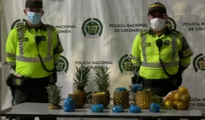 Dos uniformados frente a parte de las piñas incautadas en cuyo interior había marihuana.
