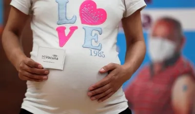 Una mujer embarazada muestra su carnet de vacunación tras recibir la vacuna de Pfizer contra la Covid-19