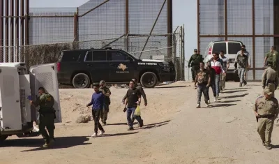 Migrantes detenidos son llevados este jueves por miembros de la Patrulla Fronteriza estadounidense a un vehículo, junto al muro fronterizo en El Paso, Texas 
