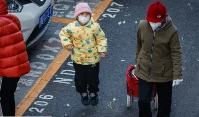 Un niño y una mujer con tapabocas a la salida de un colegio en Pekín