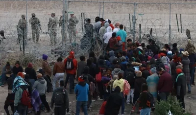 Migrantes tratan de cruzar las vallas fronterizas en Ciudad Juárez.
