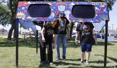 Una familia mira a través de un par de gafas gigantes especiales para el eclipse solar en el Veterans Memorial Park en Dripping Springs, Texas