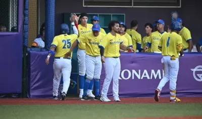 Peloteros de Colombia celebran una carrera en el dugout.